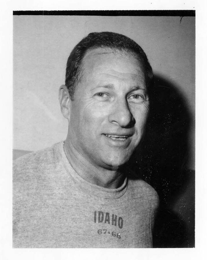 A portrait of University of Idaho football coach wearing a Vandal shirt printed with the years '67 and '68.