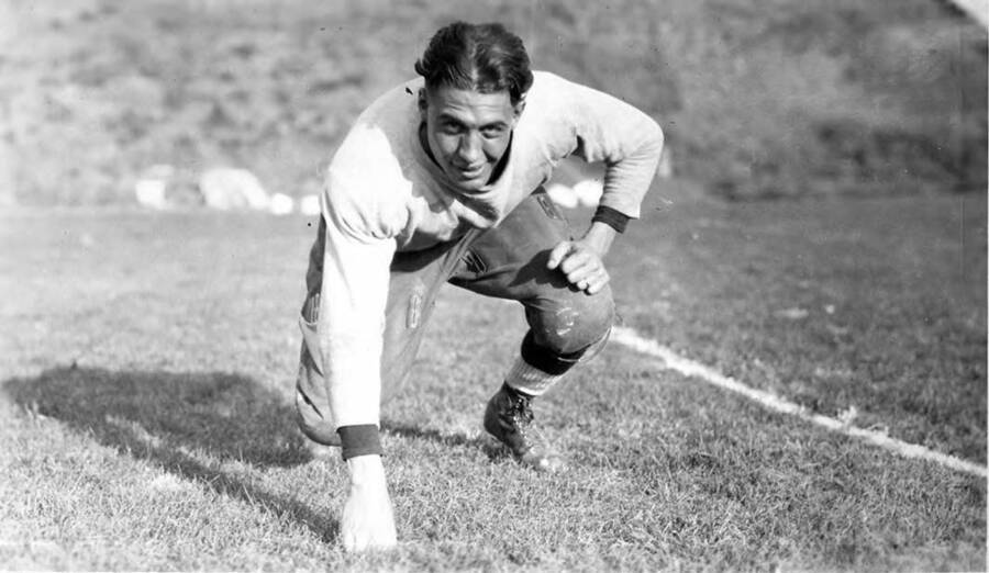 A University of Idaho football player crouches with one hand on the field.