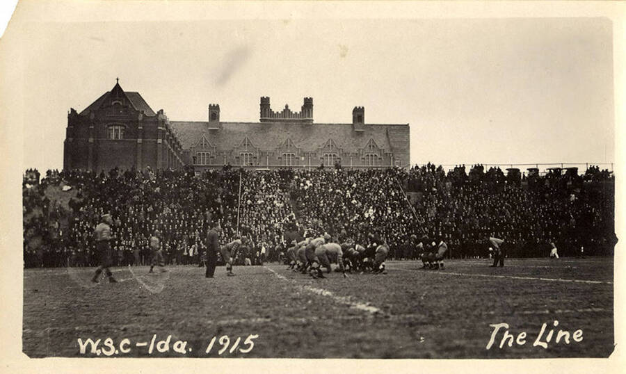 A crowded audience watches on as the teammates line up during the football game between the University of Idaho and Washington State College. The game took place on the field in front of the administration building on the U of I campus.