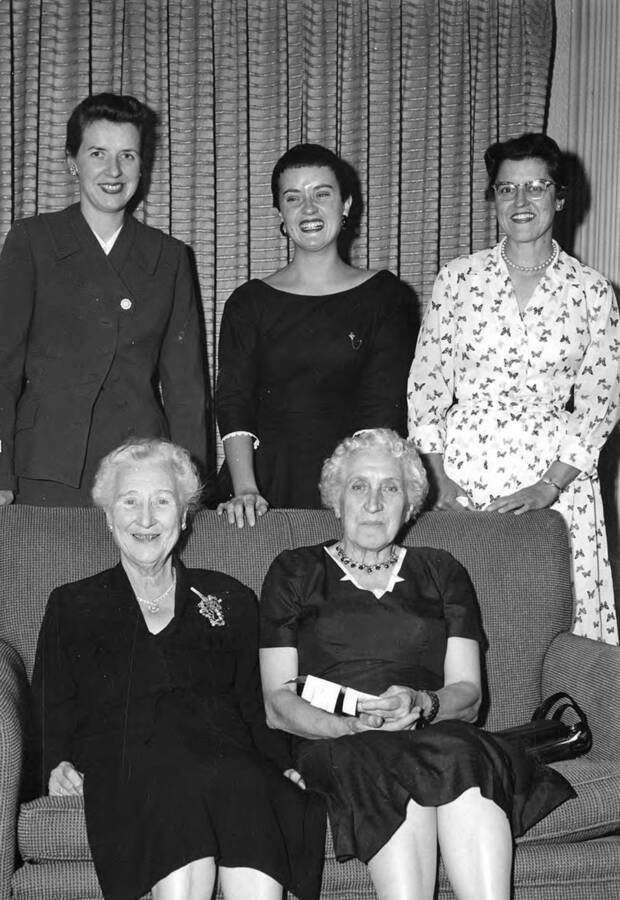 Former members of Kappa Alpha Theta posing together for a photograph at the Kappa Alpha Theta house. Standing, l-r: Jo Ann Thompson, Lorraine Langdon, June Ramstedt. Seated, l-r: Maud Iddings, Gertrude Axtell.