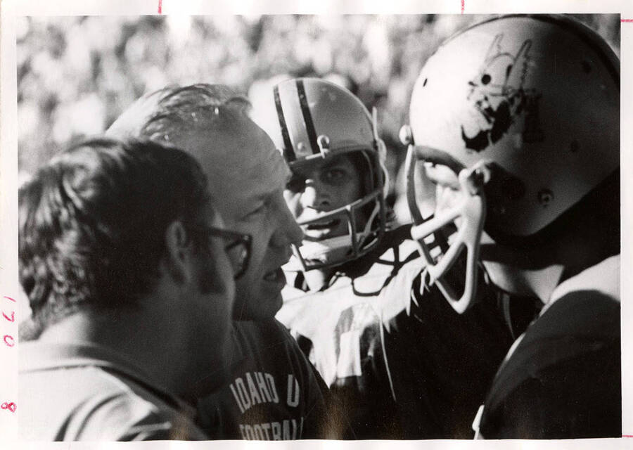 A University of Idaho football coach talks and prepares his players on the sidelines during a game.