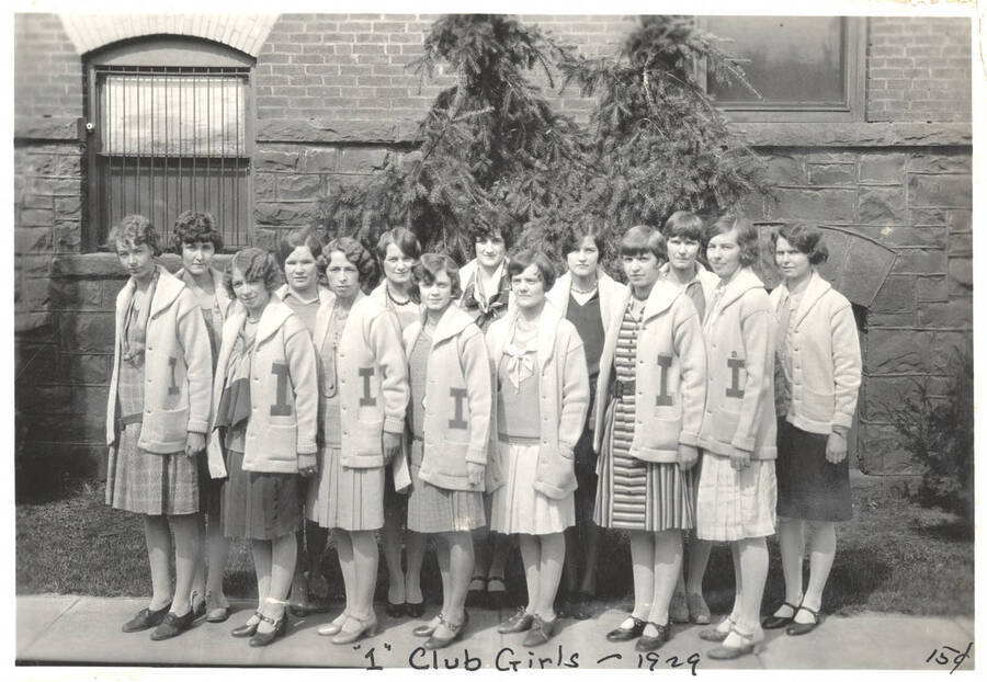 I Club members standing outside of the Women's Gym for a group photo. Caption reads ''I' Club Girls ~1929, 15 cents'.