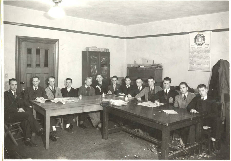 The  Press Club poses for a group photo while seated at tables. Individuals identified from left to right: Charles Warner, Harold Boyd, Albert Anderson, Conrad Frazier, Philip Hiaring, Earl Bopp, Maurice Malin, James Crawford, Hugh Eldridge, John Lukens, William McCrea, Bruce Bowler, Dwain Vincent