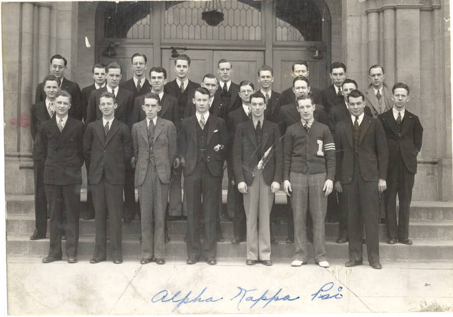 Alpha Kappa Psi members stand for a photo on Memorial Gym steps. Alpha Kappa Psi is a national professional commerce fraternity. Individuals identified as listed. Front: D. Kendrick, R. Lyons, M. Malin, L. Gaffney, L. August, C. Geraghty, W. Rich; middle: J. Holt, R. Herman, D. Linehan, S. Summers, W. Wilde, E. Hargraves, D. Barton, R. Ashbrook; back: J. Aram, L. Kraemer, T. Painter, J. Hannah, R. Jaggard, etc