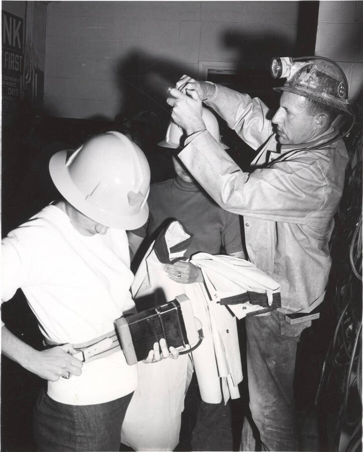 Donning hard hats and lights for descent into the heart of the Coeur d'Alene mining district, Gordon Miner attaches a battery-powered light to his wife's helmet.