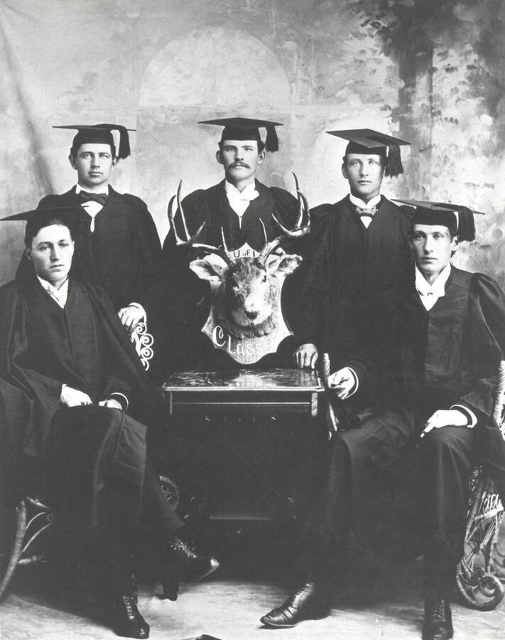 Members of the class of 1897 pose with a mounted deer head. The plague reads: 'U of I Class 97'.