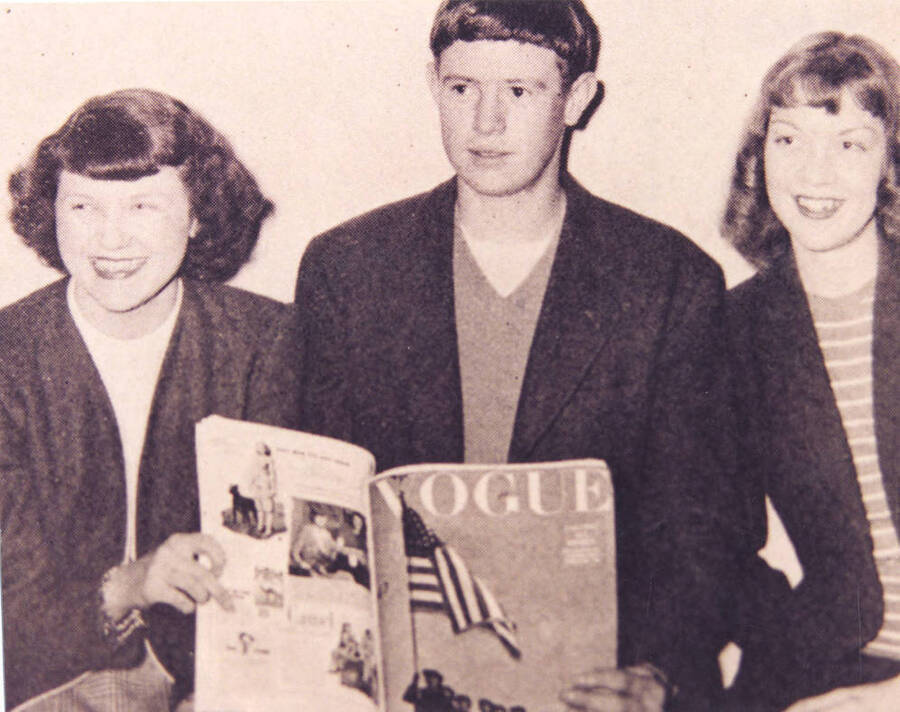 Three students pose for a photograph while holding a Vogue magazine.
