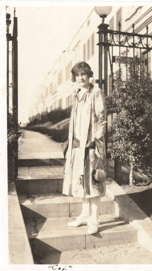An unidentified woman stands at the entrance to a gated pavilion reading 'Colonial Place'. The caption at the bottom of the photograph reads 'Col'.