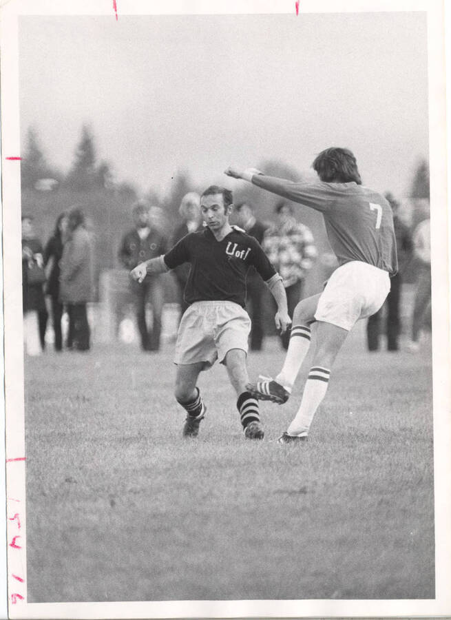 A press copy photograph of a University of Idaho soccer player guarding against an opposing team player.