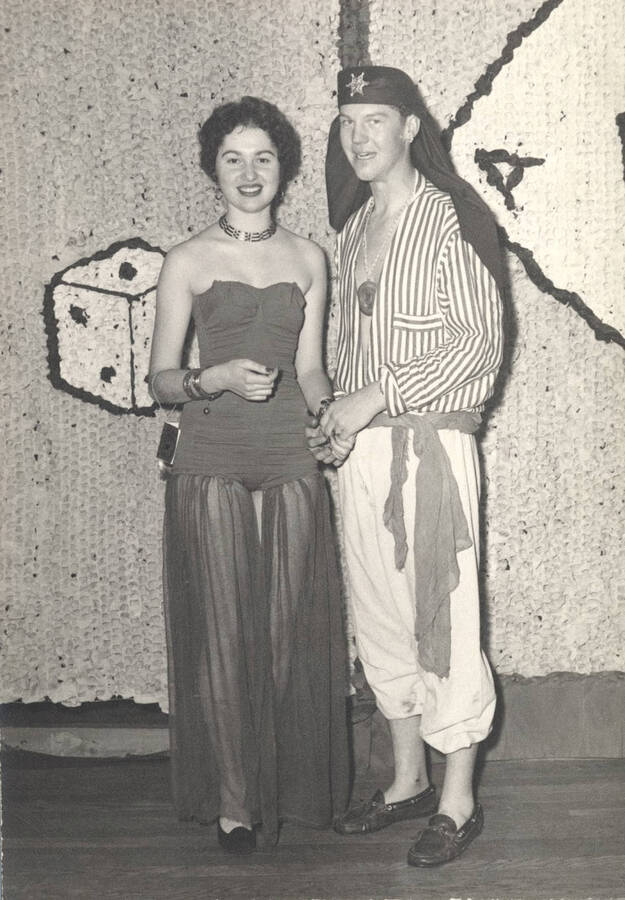An unidentified Beta Theta Pi member poses with his date before a themed dance.