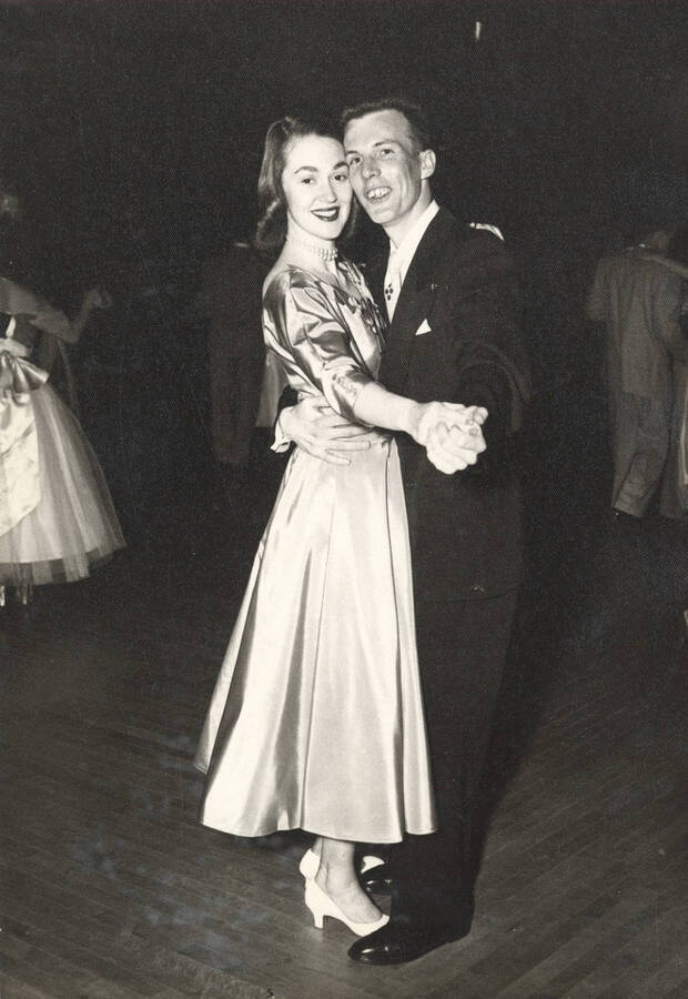 An unidentified couple pauses from dancing to take a photograph in their formal wear.