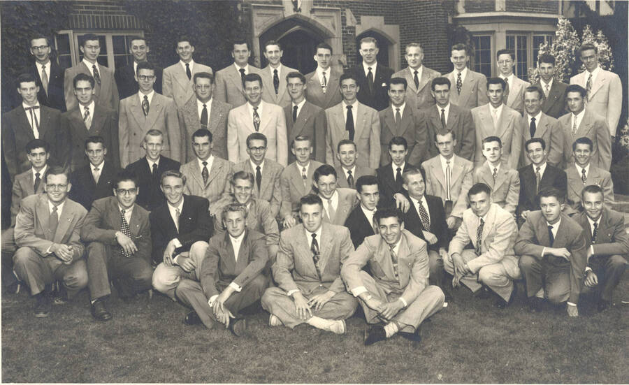 Members of the Beta Theta Pi fraternity pose for a group photo outside of their house.