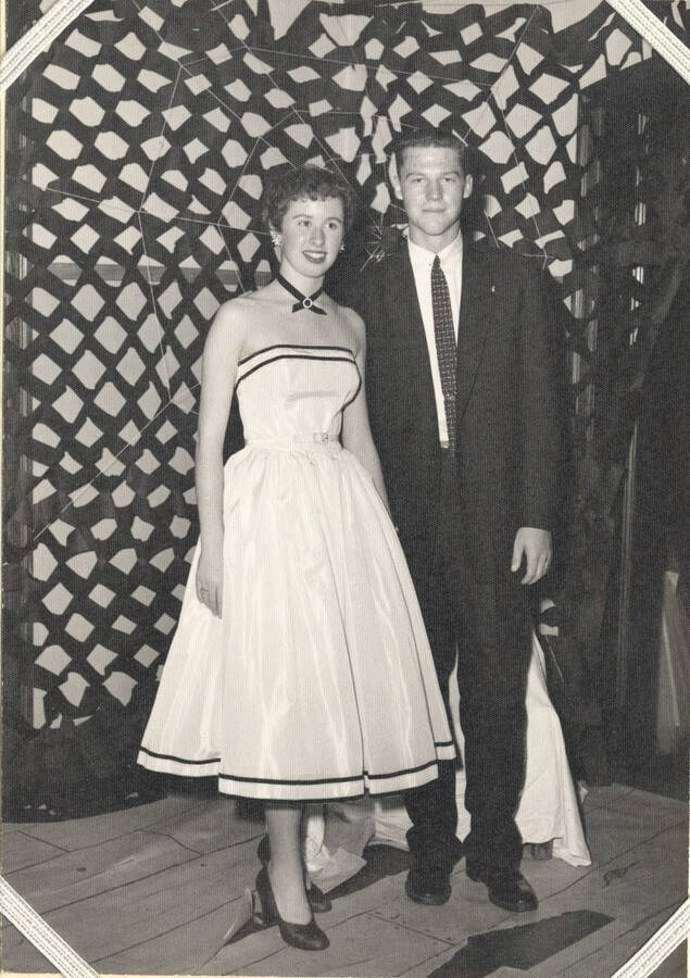 An unidentified couple pose for a photo in front of netted decorations.