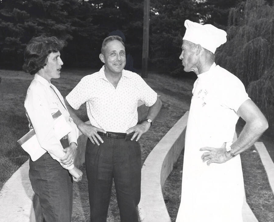 Eric B. Kirkland, organizer of the all campus barbecue, speaks with University of Idaho President Hartung and his wife in the old arboretum.