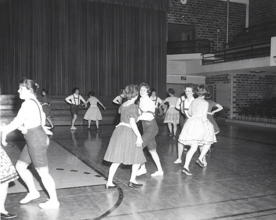 Women dance in pairs in the Memorial gym during the folk dance festival.