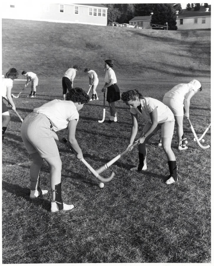 Women pair up to practice field hockey on MacLean field.