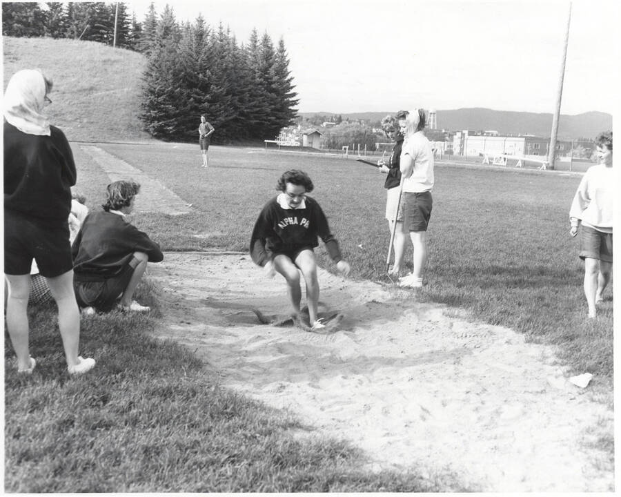 A woman competes in the long jump during a track meet.
