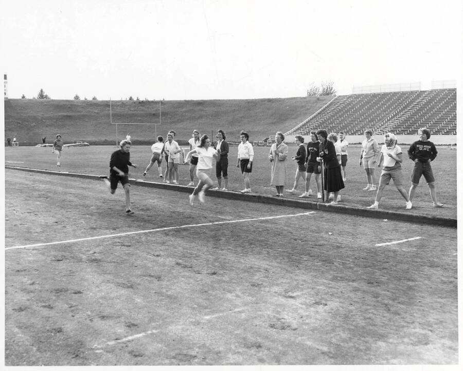 Two women compete in a race on MacLean field during a track meet.