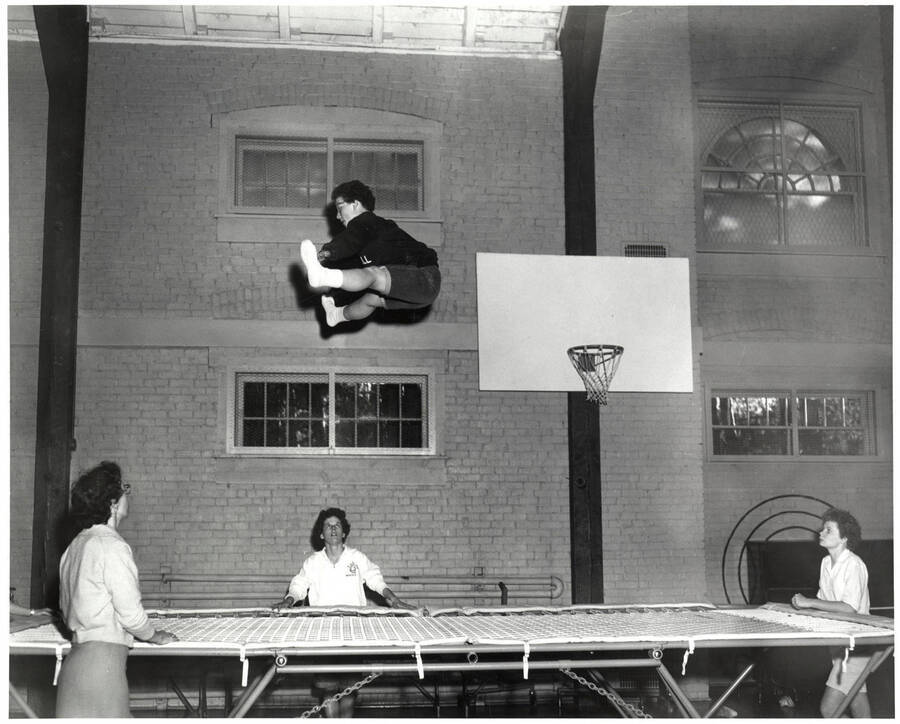 A woman jumps on a trampoline and executes a split in the Women's Gymnasium as part of the Women's Recreation Association.