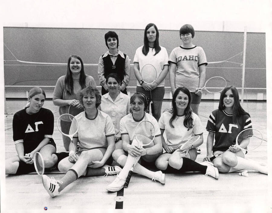 The Women's Recreation Association badminton team poses for a group photo in a gym while holding their rackets.