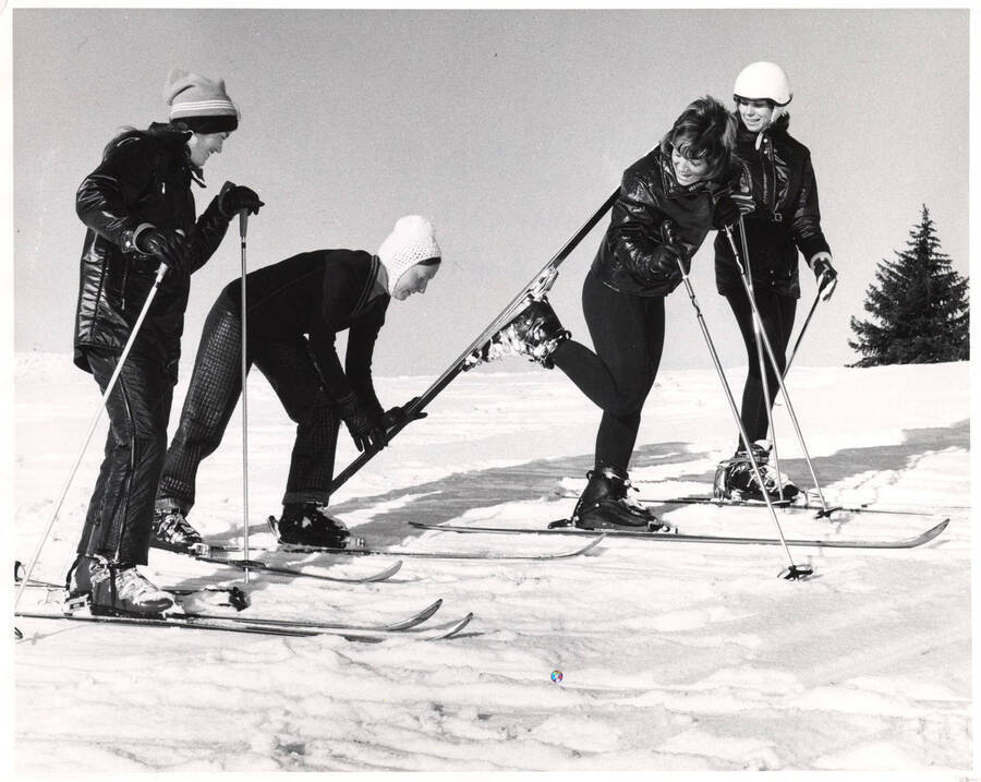 The Women's Ski team pauses on a slope to check on another member's ski. Pictured: Bobbie Kaye Downend, Rhonda Jensen (captain), Chris Smith, Jonalea Bouse. Not pictured: Jan Peck and Chris Long.