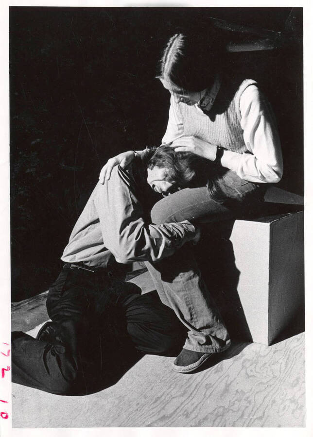 Two theatre students perform an emotional scene where one of the students is crying into the lap of the other student.