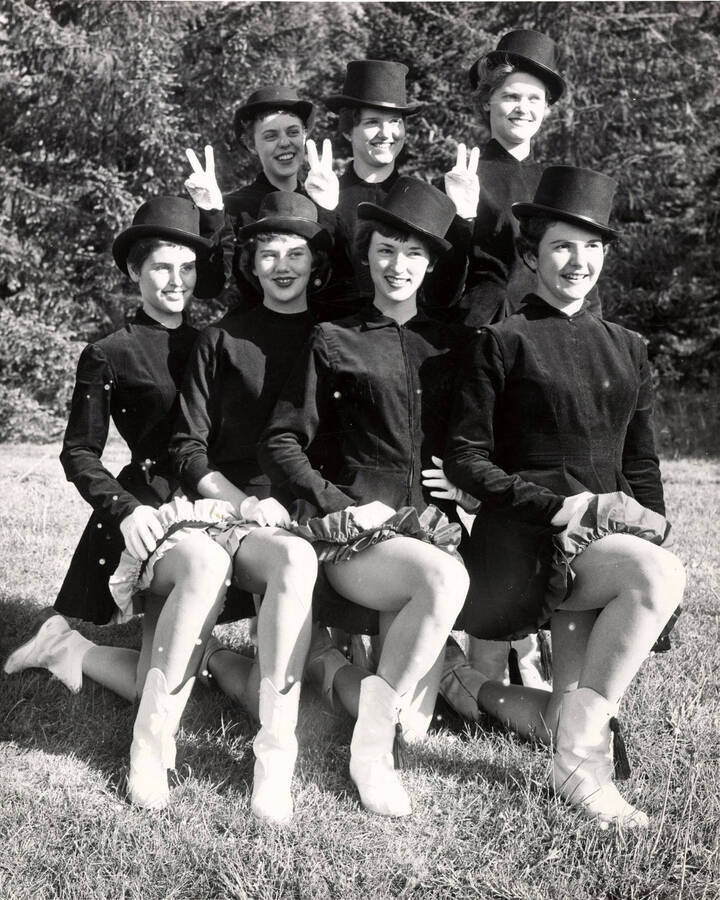 Seven Vandalettes pose for a photo together wearing their unform. The women in the back hold up a V with their fingers for Vandals.