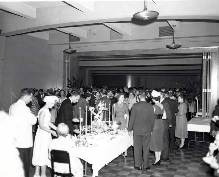 Faculty members get tea and punch from a table in the foreground while other faculty members converse in a large crowd in the background.