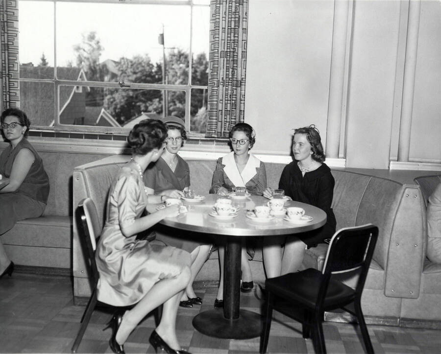 Four unidentified women sit at a table during the Freshman women's tea.