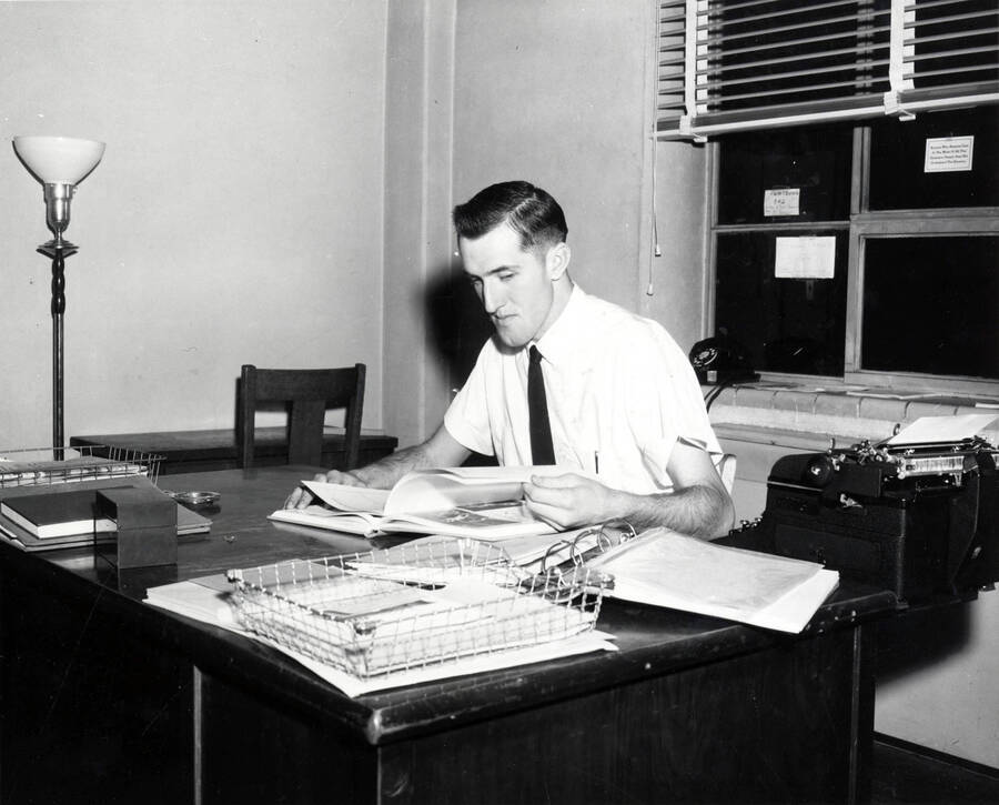 Warren Dale Reynolds, co-editor of the Gem of the Mountains yearbook, looks over a print of the yearbook at his desk.