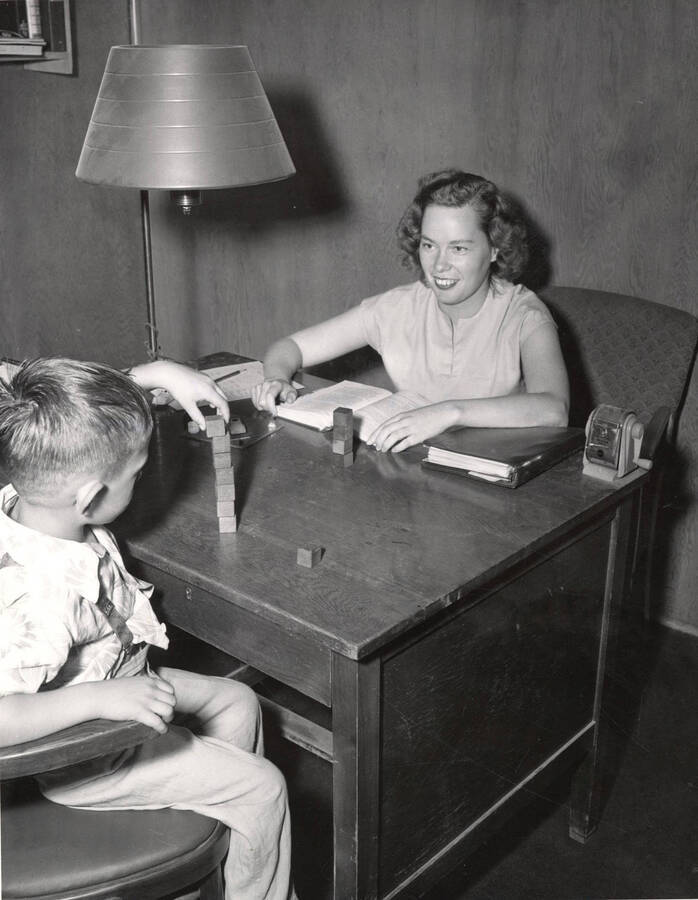 Mabel Merrel tests a childs intelligence using the Stanford-Binet test during the Summer Child Guidance Clinic.