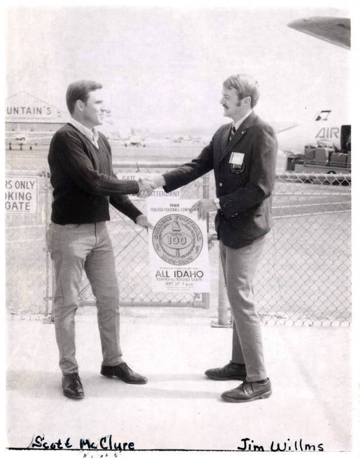 Scott McClure and ASUI President Jim Willms shake hands while holding a sign for 'All Idaho Week', the week of the University of Idaho versus Idaho State University football game.