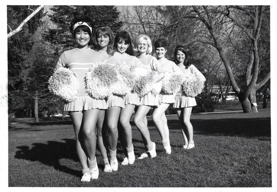 Pom-Pom Girls pose in an angled line formation on the Administration Lawn. Individuals identified from left to right: Patricia Kido, Mary Ellen Cohee, Diana Aquirre, Mary Lee Strobel, Martha Watts, and Cindy Hull.