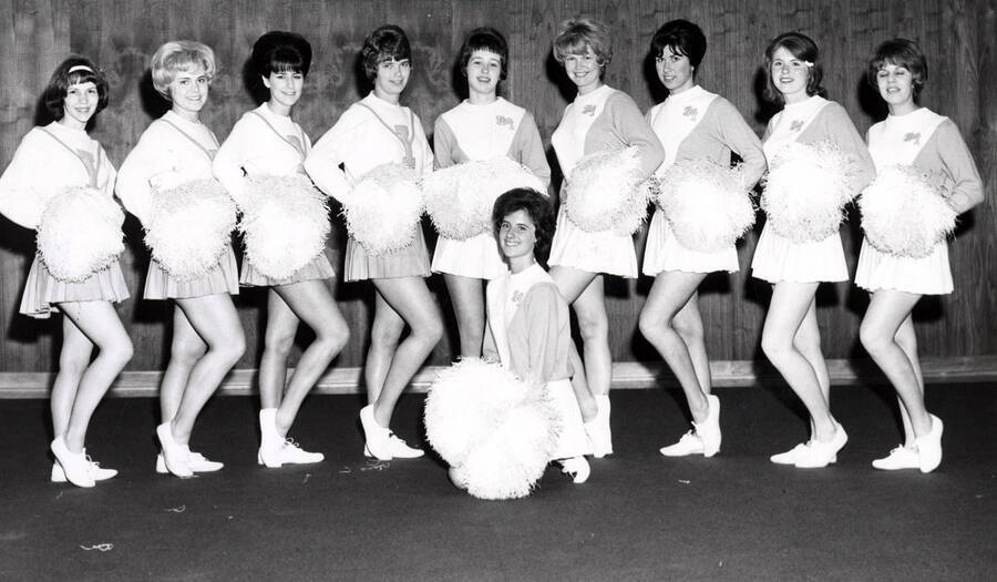 Pom-Pom Girls stand for a photo together while one woman kneels in front.
