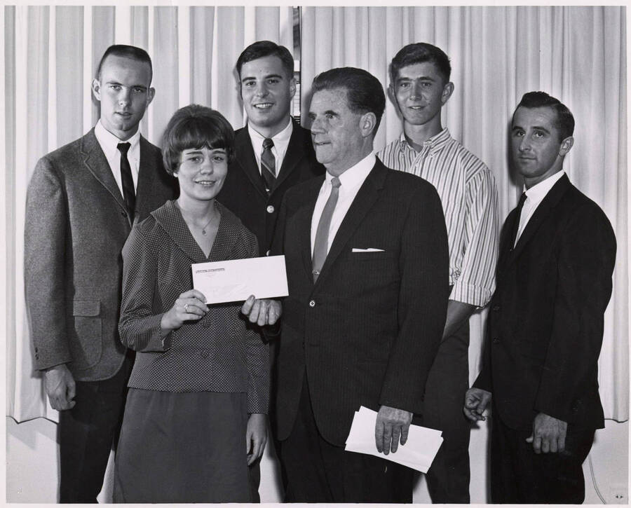 Thomas F. McManus, president of the Sunshine Mining Company, presents University of Idaho scholarships to children of mining company employees. Individuals identified from left to right: Dick Wilson, Janet Bellamy, John Magura, Jr., Gregory Dionne, and Larry Sabala