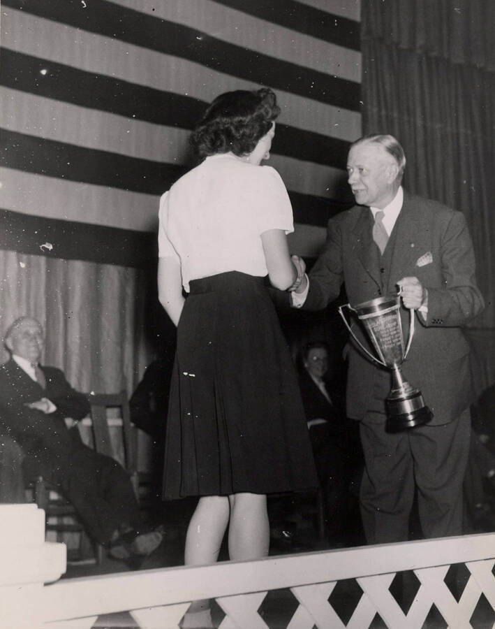 University of Idaho student Mary Jane Hawley receives a scholarship cup from President Harrison C. Dale.