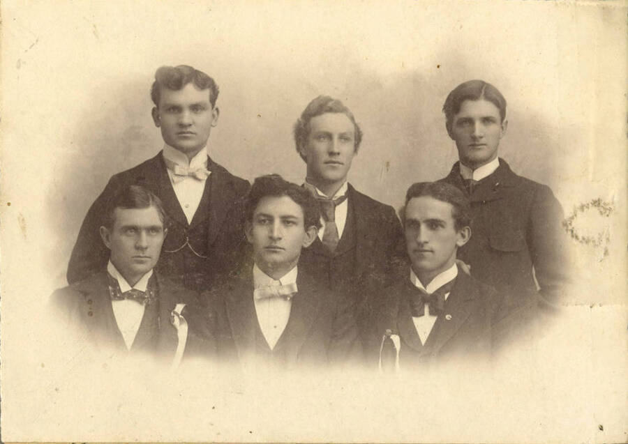 Whitman College and University of Idaho debate teams pose for a group portrait together. Individuals identified as listed. Top row (left to right): Glenn McKinley, Murray Reese Hattabough. Front row: Guy Wolfe.