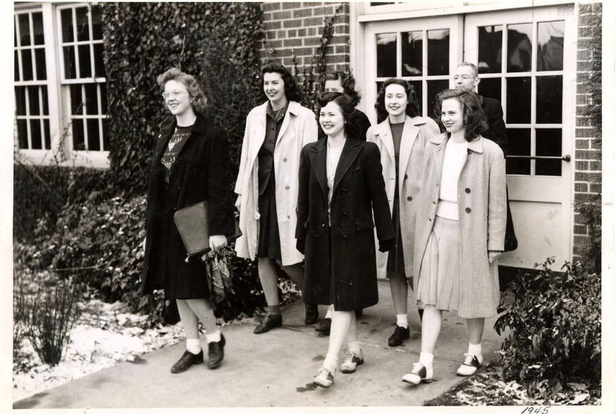 The women's debate team walks out of an unidentified building with their coach.