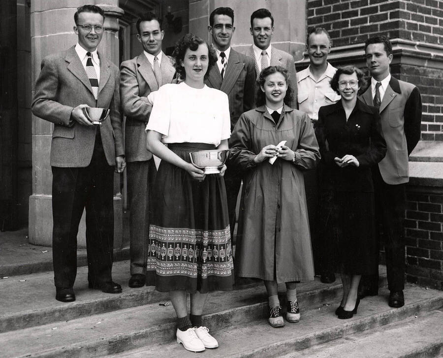 Nine seniors pose for a group photo outside of the Adminstration Building after receiving their awards. Individuals identified as listed. Front: Joanne Hofmann, Geraldine M. Early, Diana Hooper; back: Max Ririe, Leonard Winkle, Harry Howard, Richard Thomas, Robert Day, and Willard Barnes