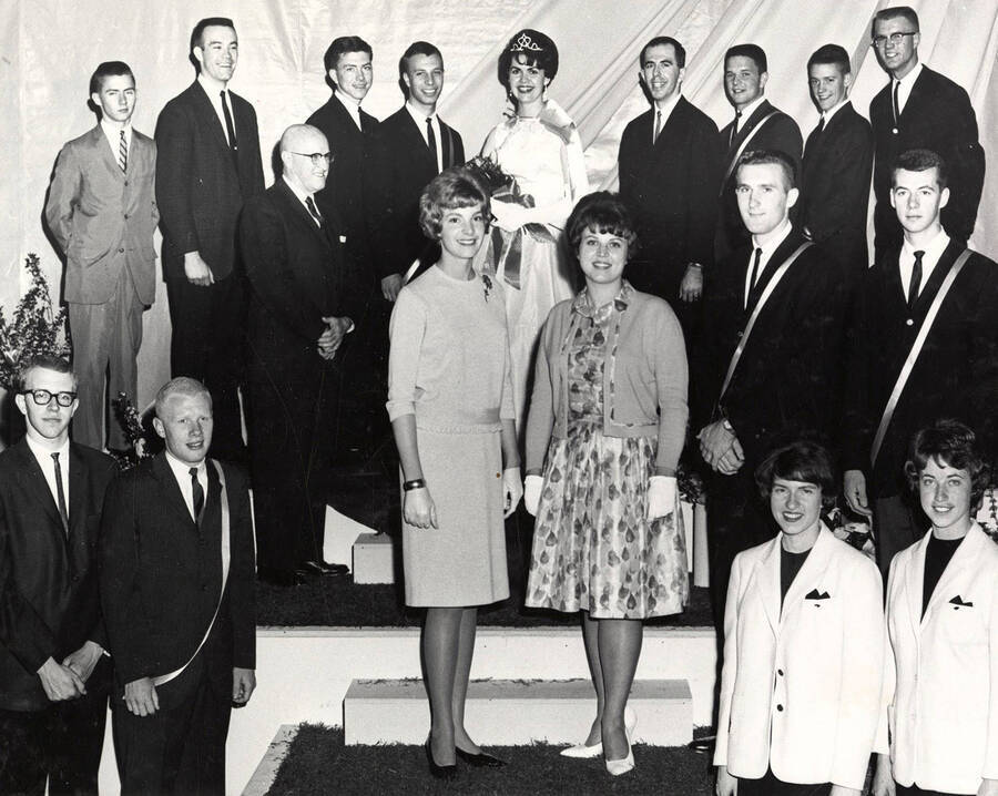 Top seniors of the class of 1962 stand on a tiered podium for a group photo. Individuals identified as listed. Top: Fred Warren, Clarence Chapman, Bruce Green, Ronald Houghtalin, Idora Lee Moore, Thomas Eisenbarth, William Bowes, James Herndon, James Metcalf; middle: President Donald R. Theophilus, Dana Andrews, Alyce Taylor, Lyle Parks, Gary Carlson, etc.