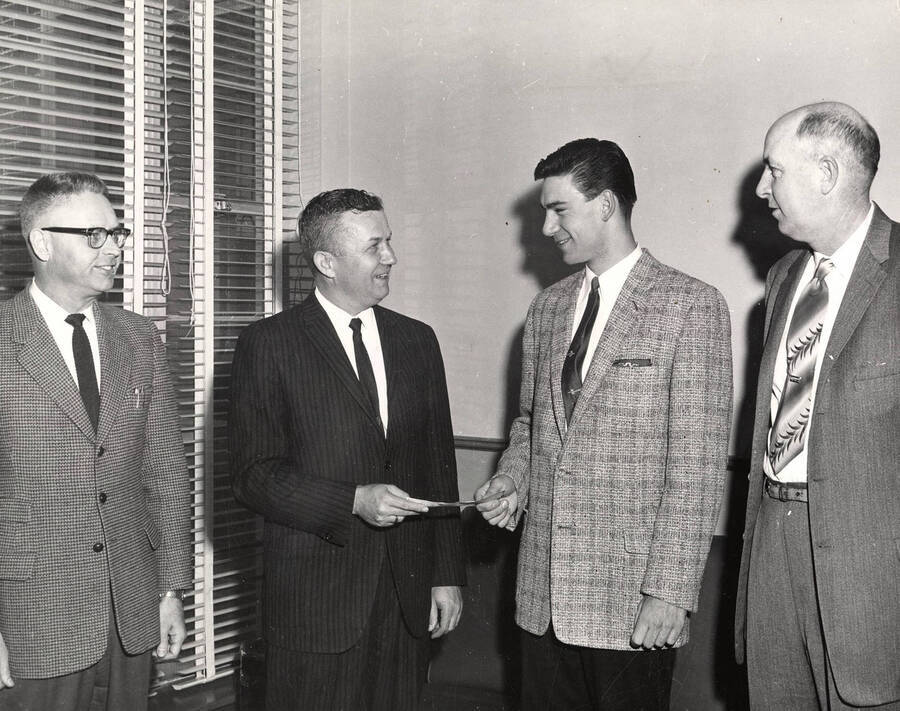A.B. Newsome awards University of Idaho student Leland Jarvis a $200 real estate award. On left is Paul O. Groke, Assistant Professor of Business Administration, and on right is Clarence O. Mercer.