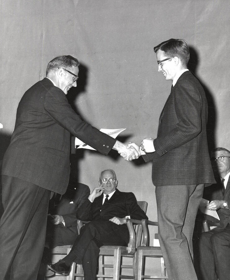 President Ernest W. Hartung congratulates University of Idaho student Keith Howard Swenson upon earning the Phi Sigma society award.