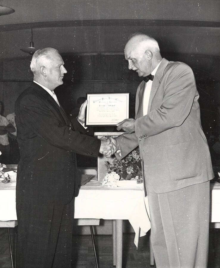 Dr. Erwin Graue (right), professor of economics at University of Idaho, receives a certificate of appreciation from D. M. Pritchett, assistant to the president of California-Pacific Utilities Co.