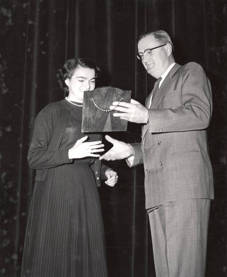 University of Idaho student Sally Rose Holz accepts the Phi Upsilon Omicron plaque from University of Idaho President Jesse E. Buchanan after being chosen as the 1952-53 Outstanding Freshman Woman in Home Economics.