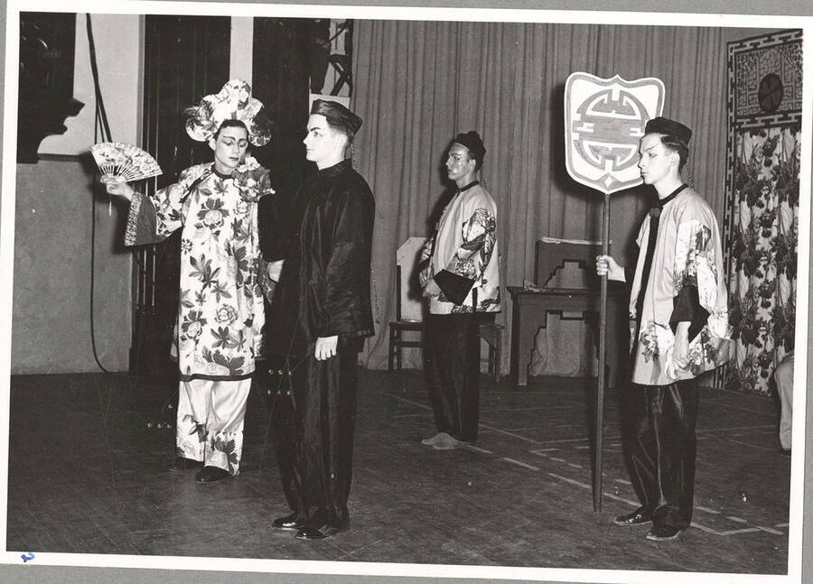 From l-r: Clyde Winters as Wu Fah Din, Andy Tozier as Property Man, Earl Mouton as Assistant Property Man, and norman Jones as Assistant Property Manager. Idaho students dressed in Chinese wear act out a scene of the Chinese play, 'The Yellow Jacket.'