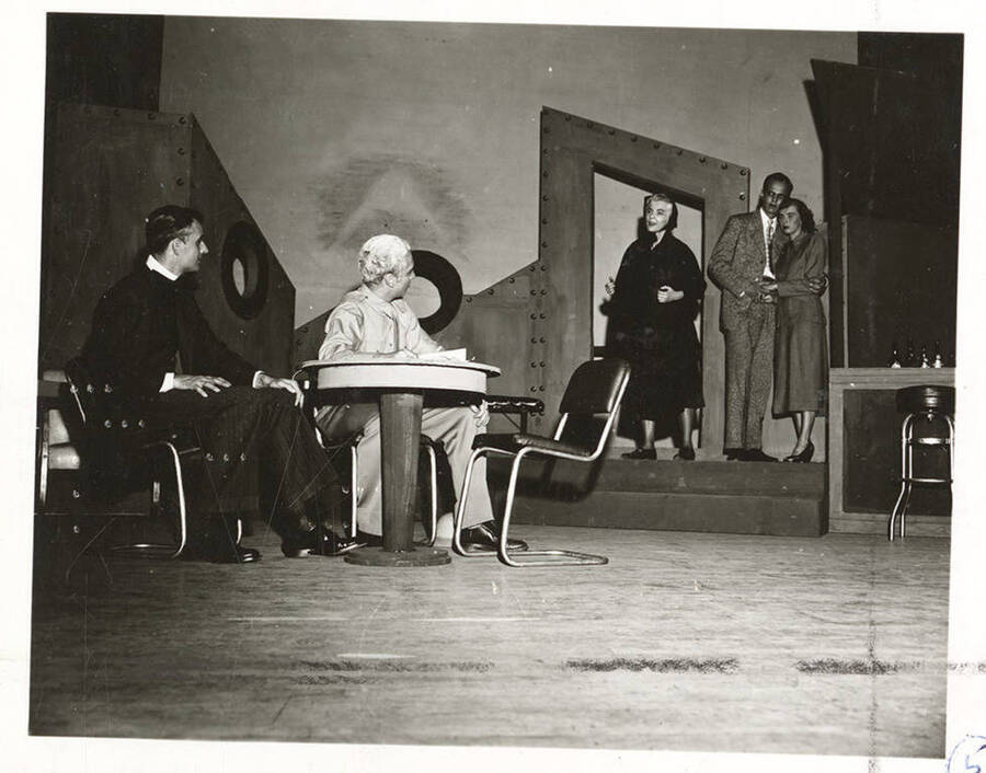 Performers identified from left -r: Guy Terwilleger as Rev. William Duke, Hugh Burgess as Rev. Frank Thompson, Larraine Cole as Mrs. Misget, Robert Bunting as Henry and Mary Thompson as Ann. Ann and Henry grasp each other while  listening to a speech Mrs. Misget gives to the reverends in Idaho drama's production of 'Outward Bound.'
