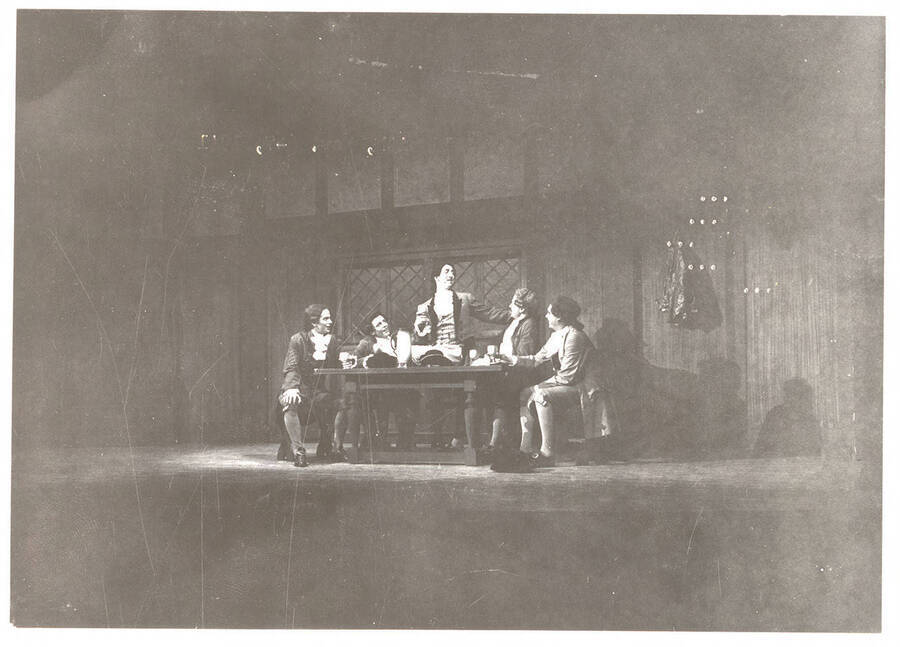 Performers from l-r: Fred Sugfriedt as Aminadale, Oscar Finkelnburg as Tom Twist, Dennis Savage as Tony Lumpkin, Denton Darrow as Jack Slang, Mark Pederson as Roger. Tony Lumpkin stands to talk at the table in Idaho drama's production of 'She Stoops to Conquer.'