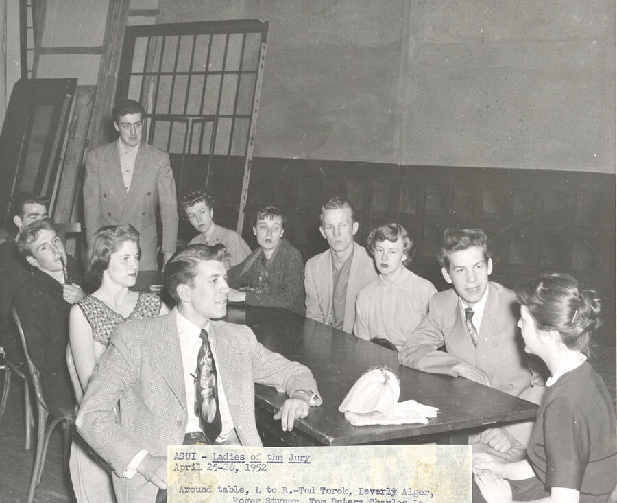 Students clockwise from left: Ted Torok, Beverly Alger, Roger Styner, Tom Butera, Charles LaFolette, Mona Rosenau, Mary Thompson, Tom Wright, Marietta Cloos, Marvin Alexander, Sharon Henderson. Idaho drama students sit at a table, acting out a group scene from the play, 'Ladies of the Jury.'