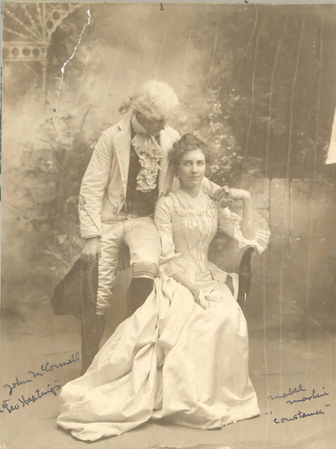 John McConnell, as George Hastings, sits on the arm of a chair and looks indearingly at Constance Neville, played by Mabel Martyn in the University of Idaho's production of "She Stoops to Conquer."
