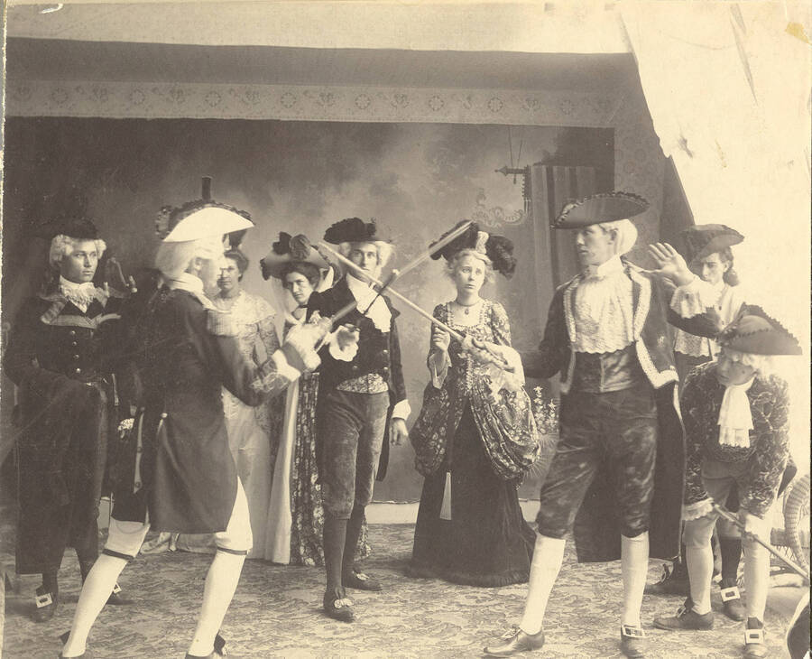 Students from left to right: Burton French, Homer David, Mabel Martyn, Edna Moore, Fred McConnell, Anna Edna Clayton, William Lee, John McConnell, Ben Oppenheim. Homer David and William Lee swordfight in Idaho drama's production of "The Rivals."